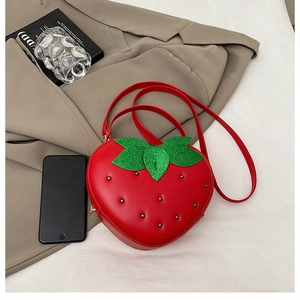 Détail du sac fraise avec feuilles vertes scintillantes et rivets noirs sur cuir PU
