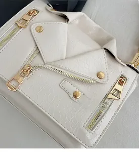 Close-up of beige crossbody bag with textured leather and gold motorcycle jacket hardware