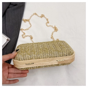 Detail of hand-woven beige straw evening clutch bag with wooden frame and gold chain strap
