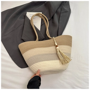Macro detail of gradient woven texture and bohemian tassel charms on a shoulder bag
