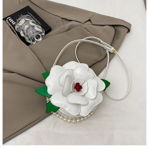 Detail of white camellia floral crossbody bag with pearl trim on a stylish suit