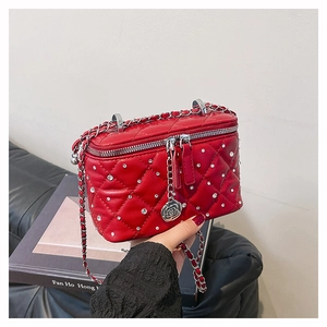 Detail of red quilted crossbody bag featuring sparkling rhinestones and rose charm