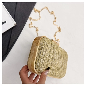 Detail of beige woven straw clutch bag with light wood side frames and golden chain strap