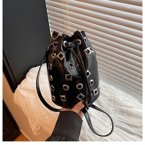 Gros plan détaillé du sac seau en cuir noir brillant avec clous et œillets en argent