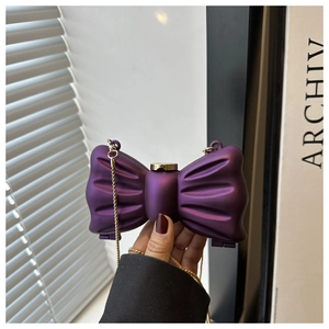 Détail du mini sac rigide violet en forme de nœud avec bandoulière dorée