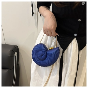 Detail view of navy blue conch shaped acrylic box bag with golden chain and spiral texture