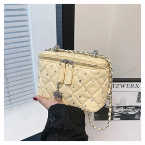 Detail of yellow quilted leather bag with rhinestone accents and camellia zipper pull