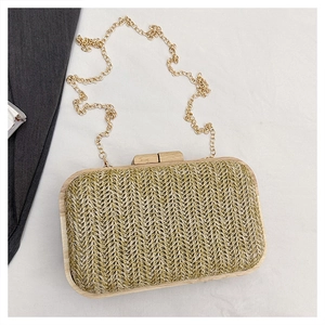 Detail of summer woven straw clutch bag with wooden frame and gold metal chain strap