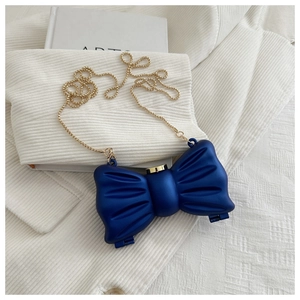 Détail de la pochette nœud bleu marine avec une élégante bandoulière en chaîne dorée
