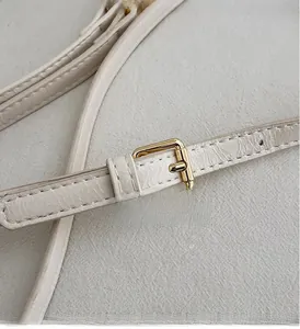 Macro shot of cream leather strap with a polished gold-tone metal square buckle