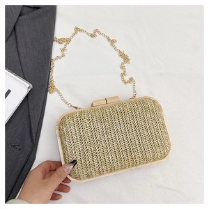 Macro detail of hand-woven straw evening bag with solid wood frame and gold chain strap