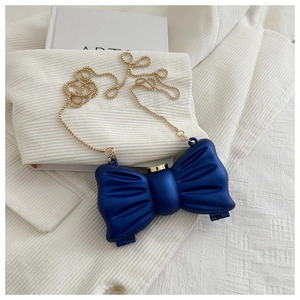 Détail de la pochette bleu marine en forme de nœud avec chaîne dorée sur un livre