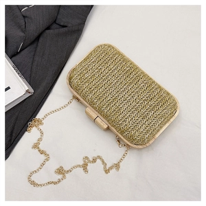 Macro view of woven straw clutch bag featuring wooden frame and golden chain strap detail