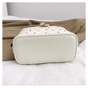 Detail view of white quilted bucket bag with silver studs and flat oval base