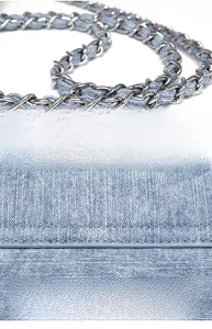 Detail of light blue denim handbag featuring silver metal chain strap and fine stitching