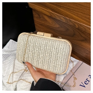 Close-up of beige woven straw clutch featuring wooden frame and gold chain strap