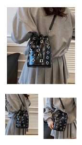 Macro detail of black patent leather bucket bag with silver metal eyelets and rivets