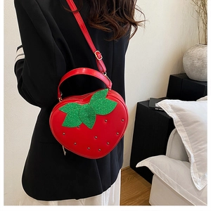 Détail du sac fraise rouge mignon avec des feuilles pailletées et des rivets en métal