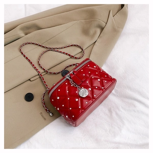 Detailed macro view of red quilted vanity case with white beads and camellia pendant
