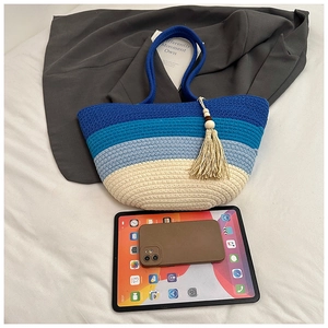 Detail view of large woven tote with blue gradient, tassels, and size comparison to iPad