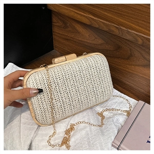Detail of beige woven straw clutch bag with wooden frame and golden chain strap
