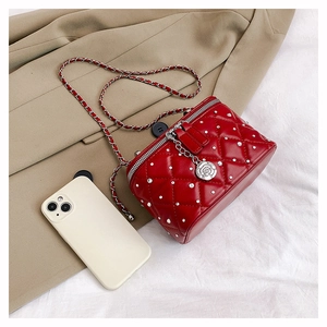 Detail of red quilted crossbody bag with rhinestone studs and rose metal zipper puller