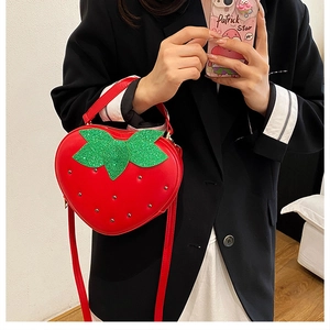 Détail du sac fraise rouge avec rivets métalliques et feuilles en paillettes vertes