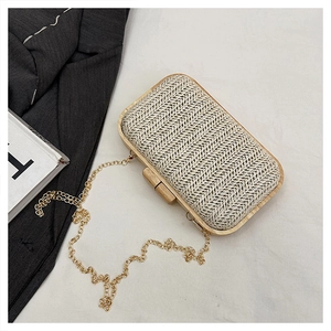 Detail of woven straw evening clutch bag with natural wood frame and gold chain strap