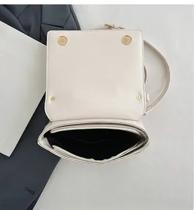 Detail view of cream PU leather crossbody bag interior with gold buckles and pocket