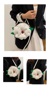 Detailed view of 3D camellia flower bag with pearl handle and contrast leaf accents