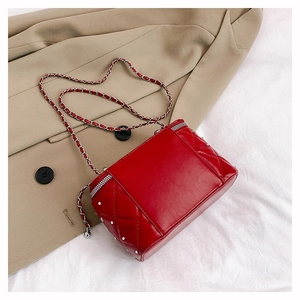 Detail of red quilted crossbody bag with silver studs and metal chain strap on blazer