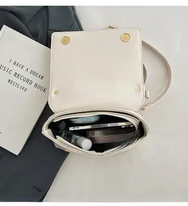 Interior view of beige leather crossbody bag showing large storage for phone and perfume