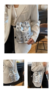 Close-up of silver punk bucket bag with metal grommets and drawstring closure detail