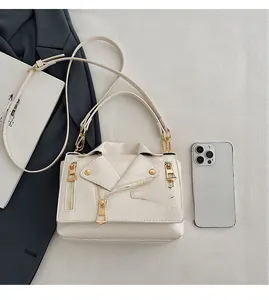 Detail of cream biker-style crossbody bag featuring moto jacket zippers and stud accents