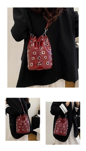 Detail of red patent leather bucket bag with silver metal eyelets and drawstring closure