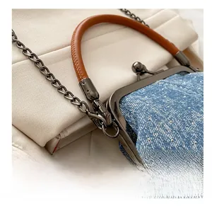 Detail of dark gunmetal hardware hook and chain strap on blue polka dot denim bag