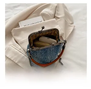 Detailed internal view of denim handbag showing capacity for phone and wallet with metal frame
