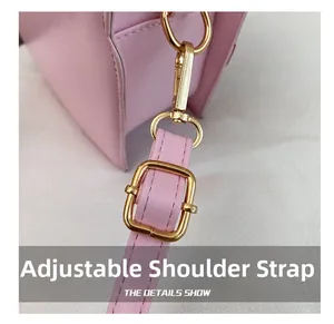 Detail of adjustable shoulder strap and golden metal buckle on pink strawberry bag
