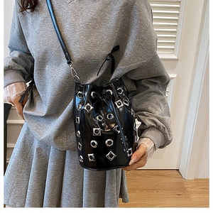 Détail d'un sac seau noir avec œillets métalliques argentés et clous carrés stylés