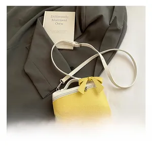Detail of yellow and beige patchwork leather bag with bow and adjustable strap