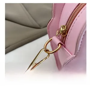 Detailed close-up of premium gold-toned metal hardware on a pink crossbody bag