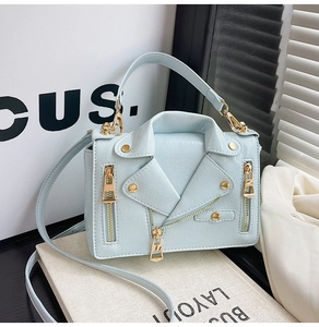 Detail of light blue motorcycle jacket style handbag with crocodile texture and gold hardware