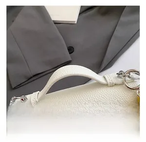 Detail of lychee pattern leather handle and silver metal zipper on colorblock handbag