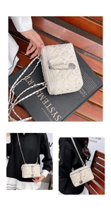 Detail of cream quilted box bag with twin zippers and metal flower charm detail