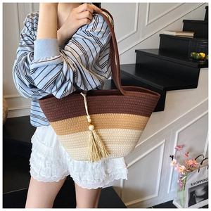 Close-up of tricolor woven tote bag with fringe tassel detail and long handles