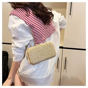 Detail view of woven straw evening bag with golden chain strap on a female model