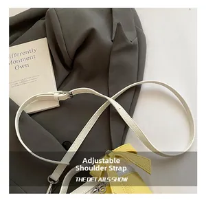 Detail of adjustable white leather strap on a yellow litchi grain handbag