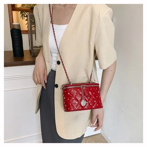 Detail of red quilted leather crossbody bag with camellia pendant and chain strap