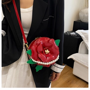 Detail of red rose-shaped crossbody bag featuring glossy leather petals and pearl chain