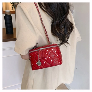 Detailed shot of red quilted crossbody bag with silver chain and floral charm